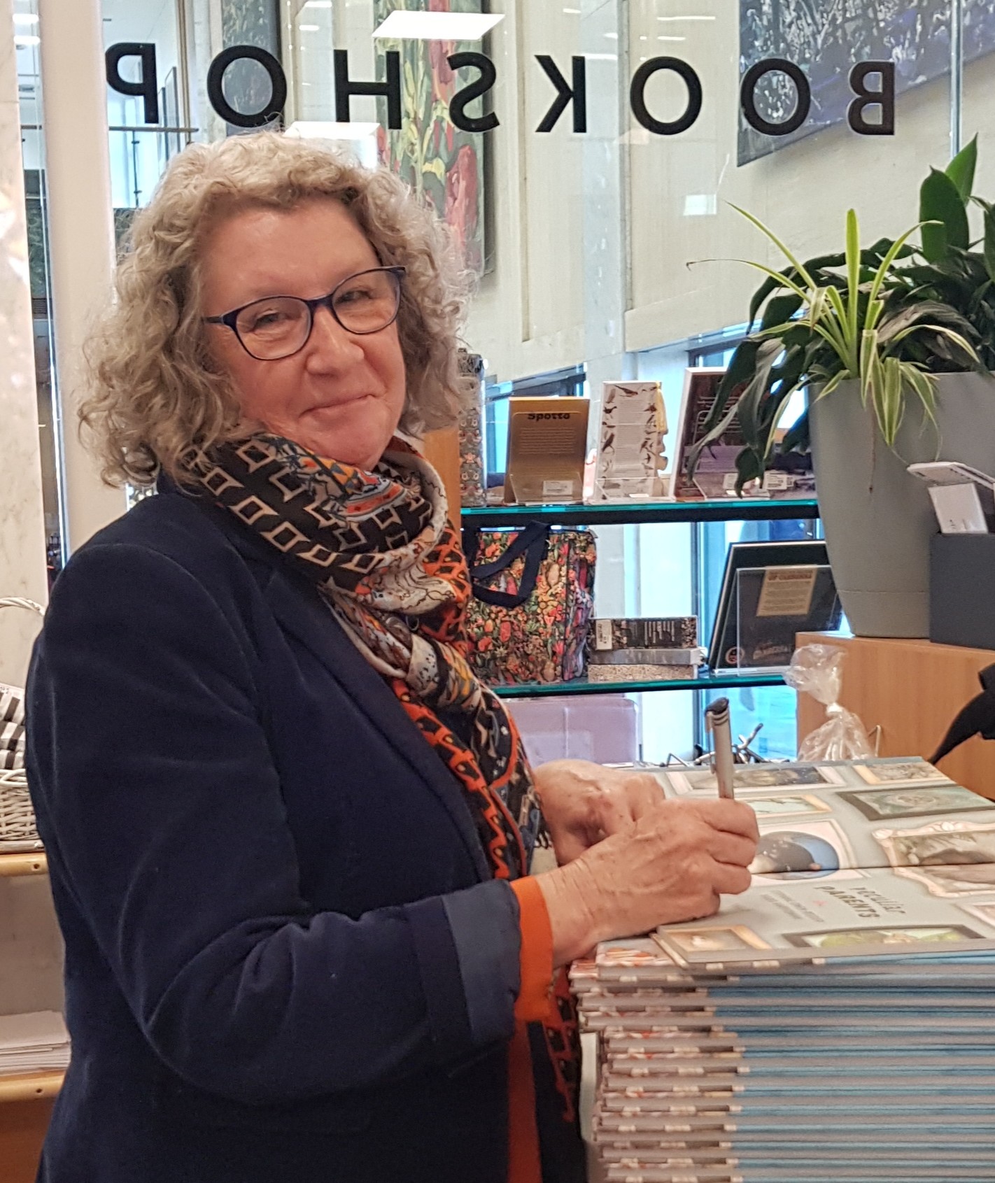 A women signing copies of her book in a bookshop