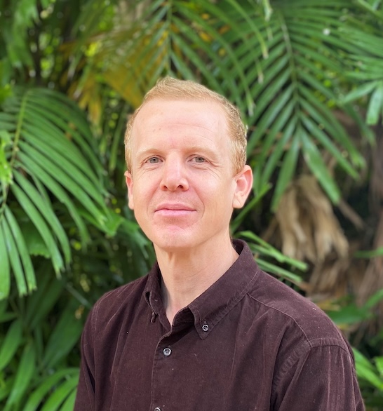 Photo of teacher and author Thomas Higgs standing in front of a garden