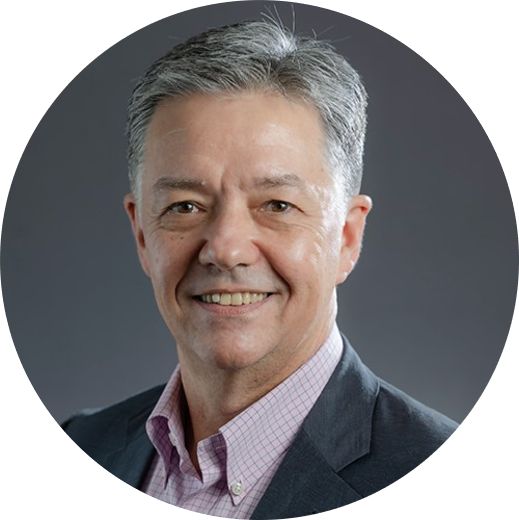 A headshot of a grey haired man where a button down shirt and a blazer, while looking at the camera