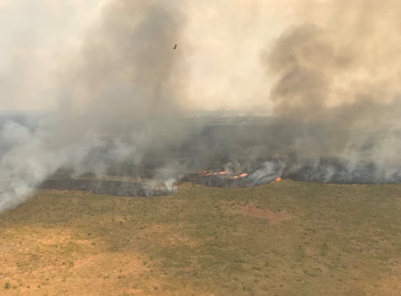 Fire and smoke on a red earth and green grass, captured in a bird's eye view