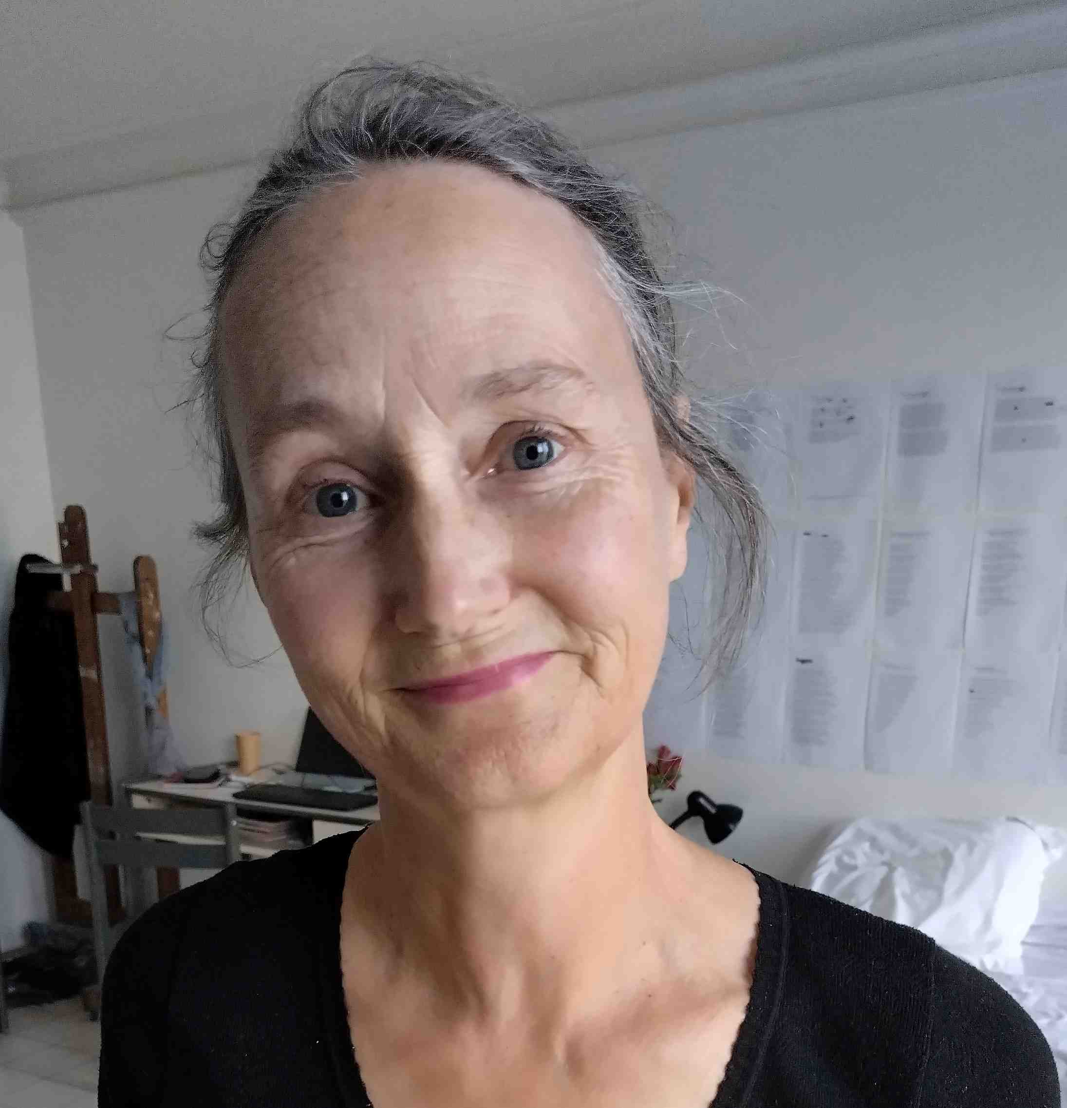 A woman with her hair tied back, wearing a black shirt