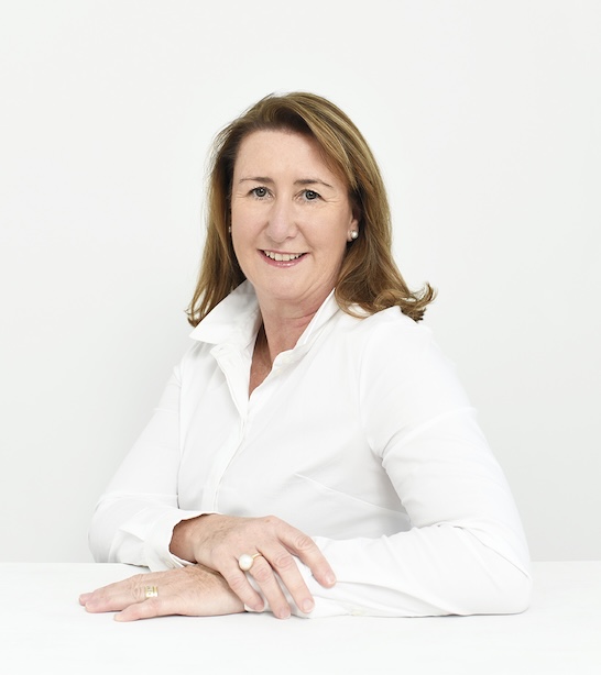 A woman in a white shirt smiling at the camera.