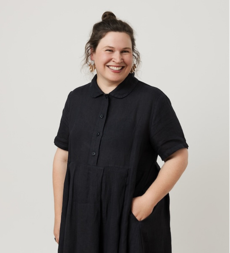 A woman wearing a black dress and smiling at the camera. 