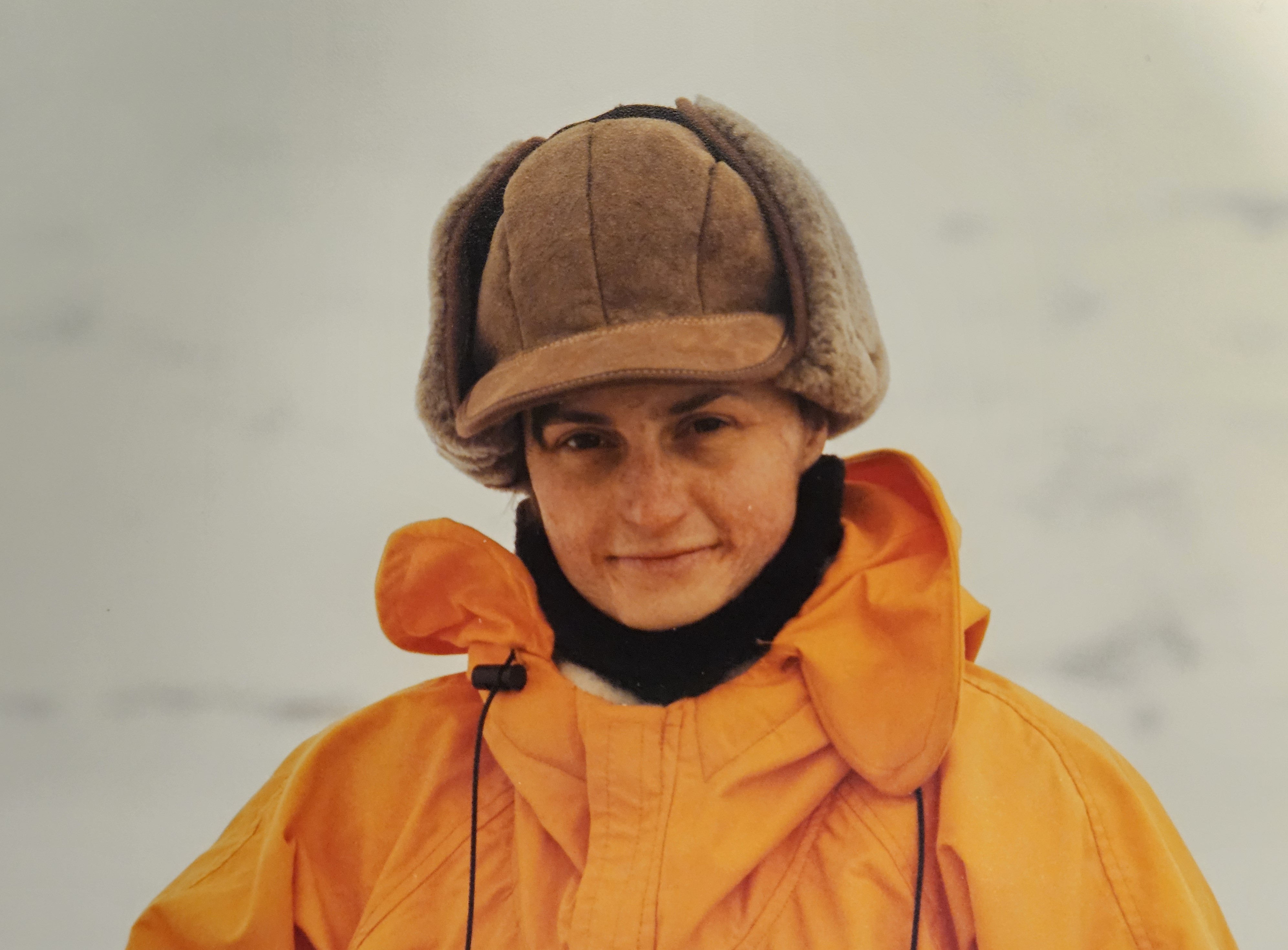 A women wearing a brown winter hat and orange coat