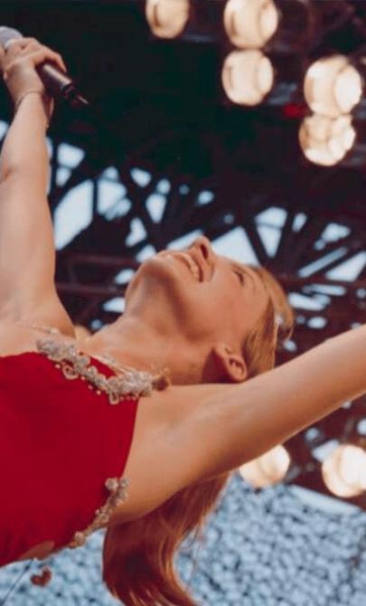 Kylie Minogue wearing a red dress and with her arms in the air