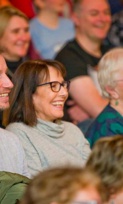 A crowd of people sitting and looking at something out of frame.