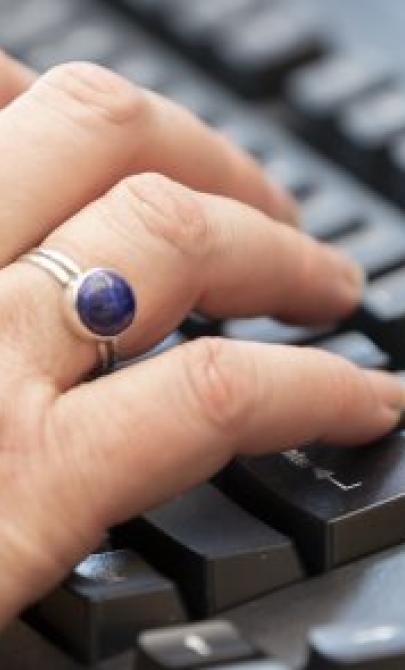 Close-up of hands typing on a black computer keyboard