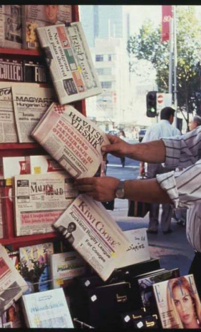 A man looking at newspapers in multiple languages at a newspaper kiosk on Elizabeth Street, Melbourne.