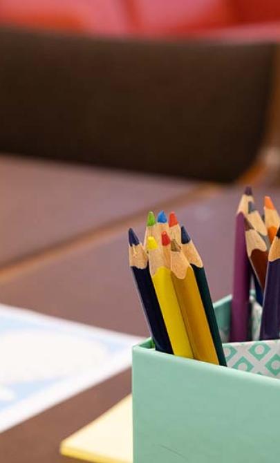 Photo of coloured pencils in a container on a desk
