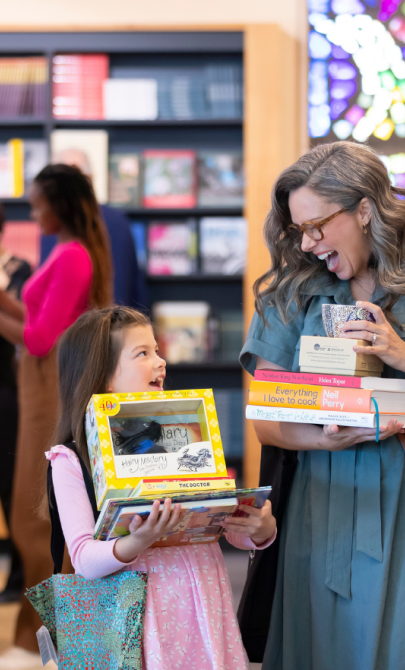 A woman and child holding books and gifts in the National Library Bookshop.