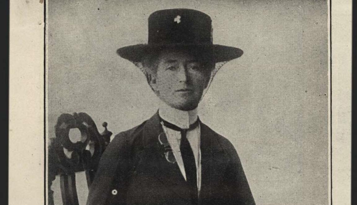 Black and white headshot of Mrs Daisy M. Bates, wearing a black hat and tie while sitting on a chair. 