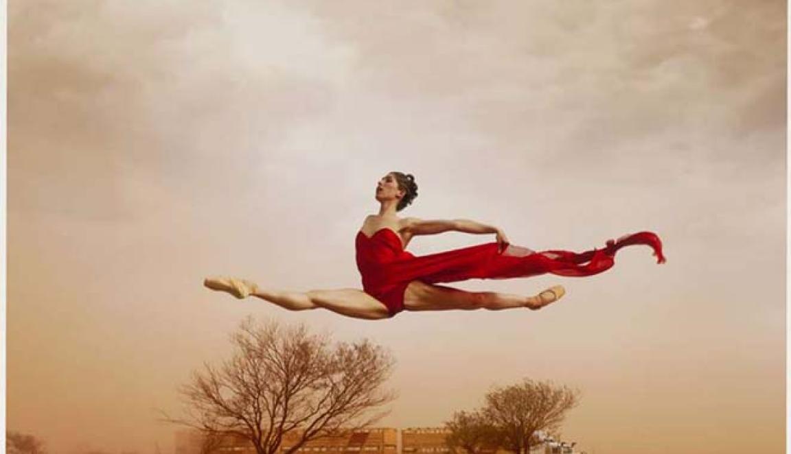A dancer leaping in the air with red desert around her