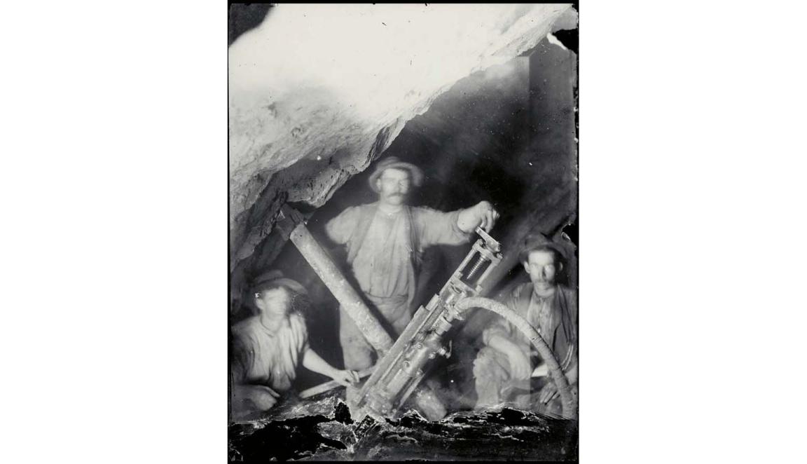black and white photograph of three miners with an early pneumatic drill