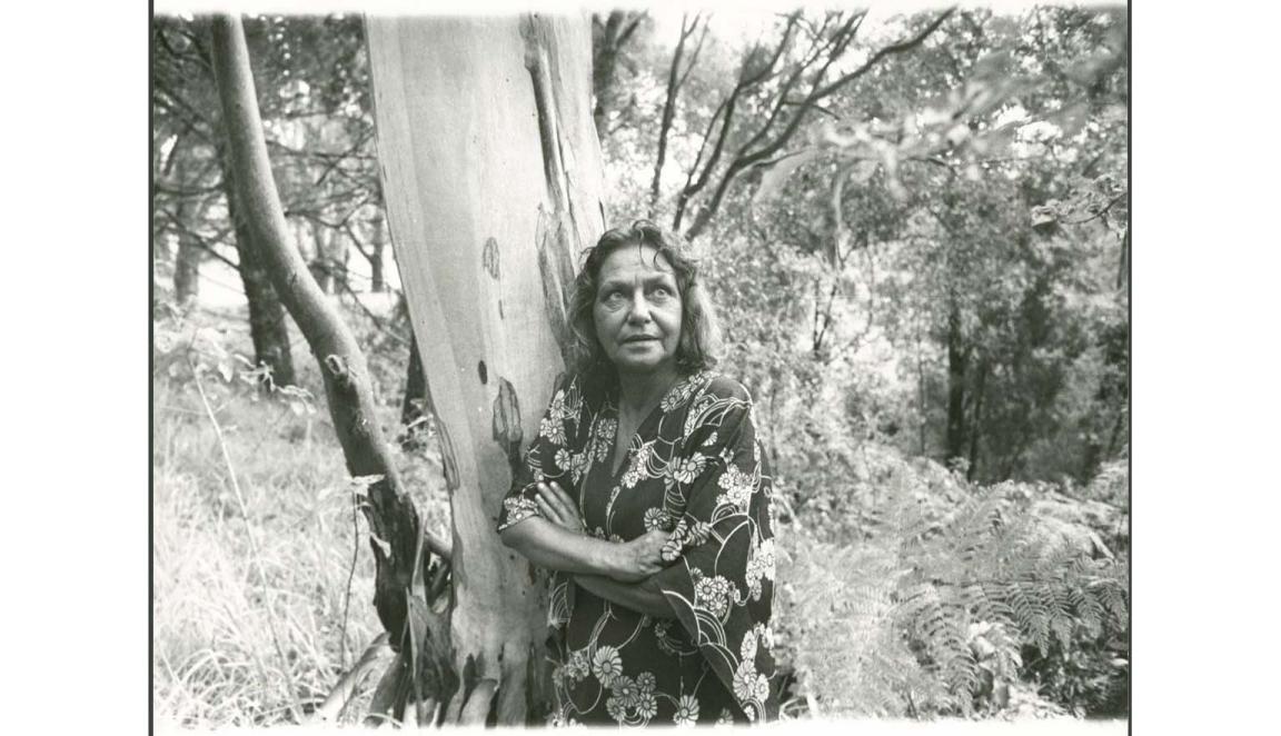 black and white photograph of an Aboriginal woman leaning against a tree