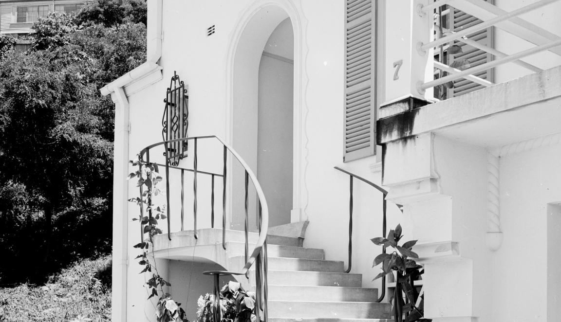 Black and white photo of a curved set of stairs leading up to the door of a house