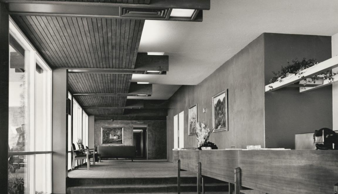 Black and white photo of the reception area of a hotel, with wooden features