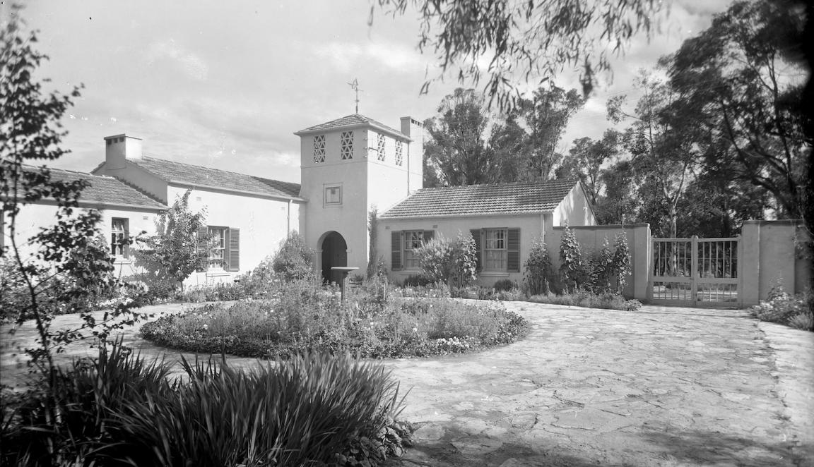 Black and white photo of a circular driveway and garden in front of a new house