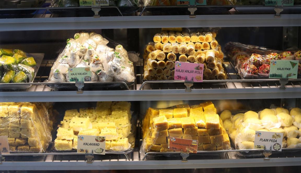 Small piles of traditional Indian sweets in a glass display case