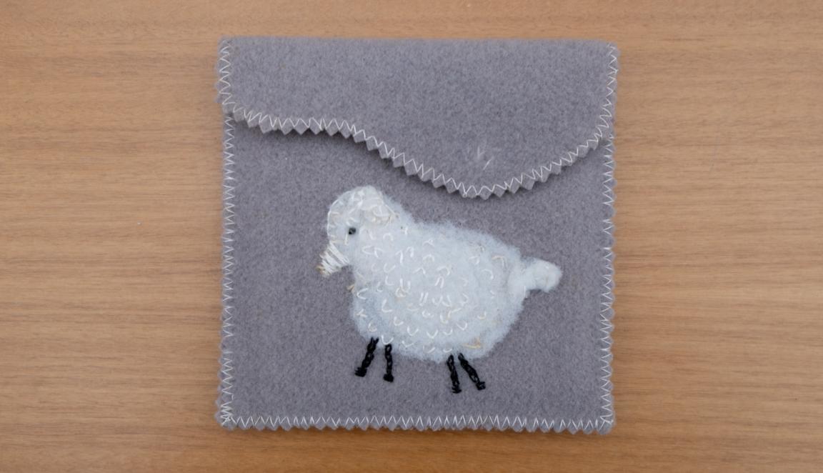 Grey felt bag with a fluffy white sheep