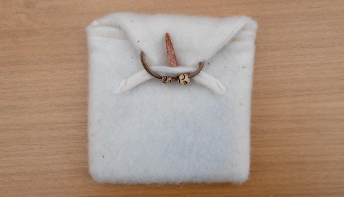 Fluffy white fabric pouch held closed with a wooden bead