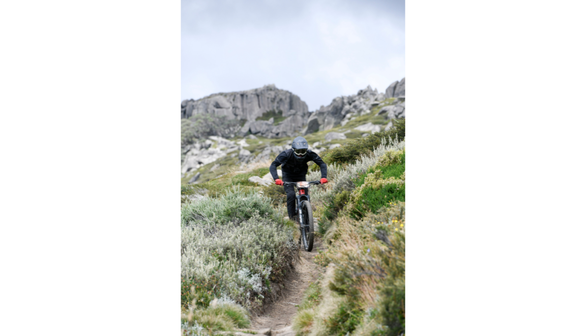 Mountain biker riding down a dirt path in a field of grass