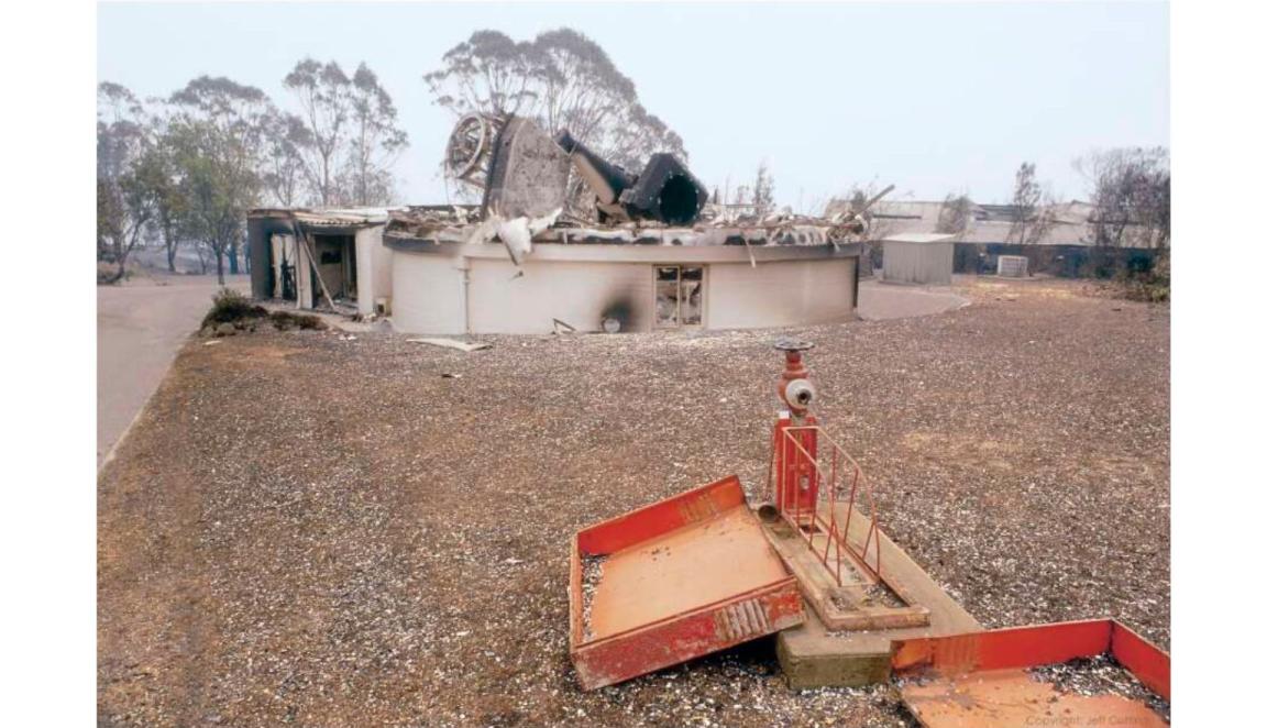  A photograph of burnt and partially collapsed structure with a burnt telescope at the centre.
