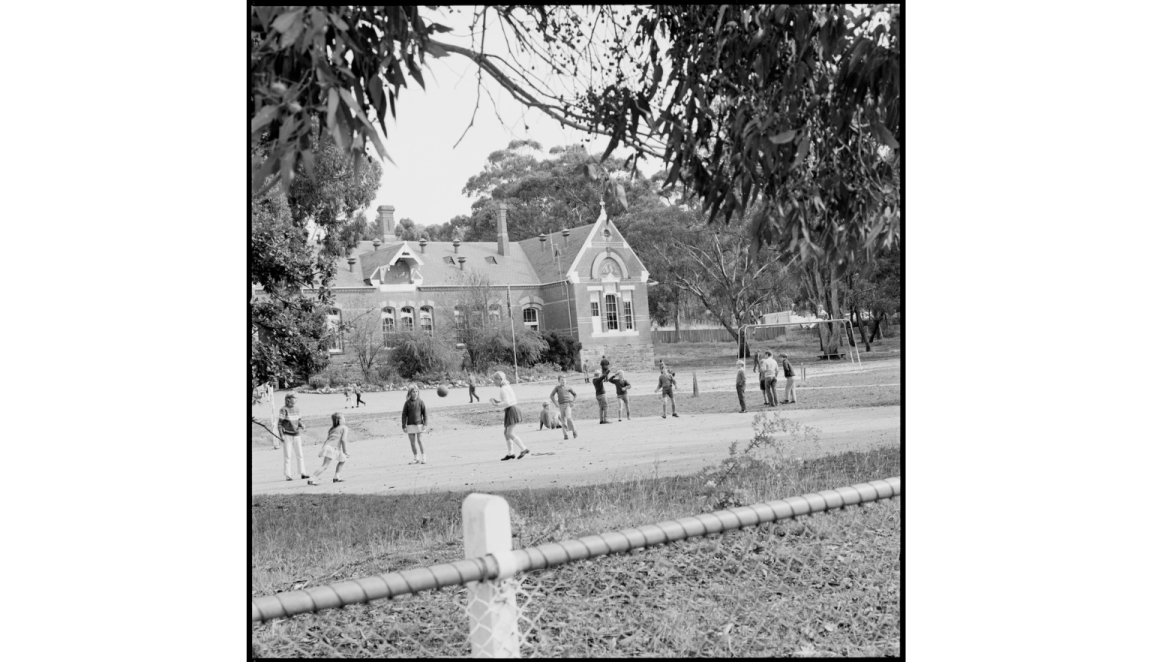 A black and white photograph of children playing in a schoolyard in Victoria