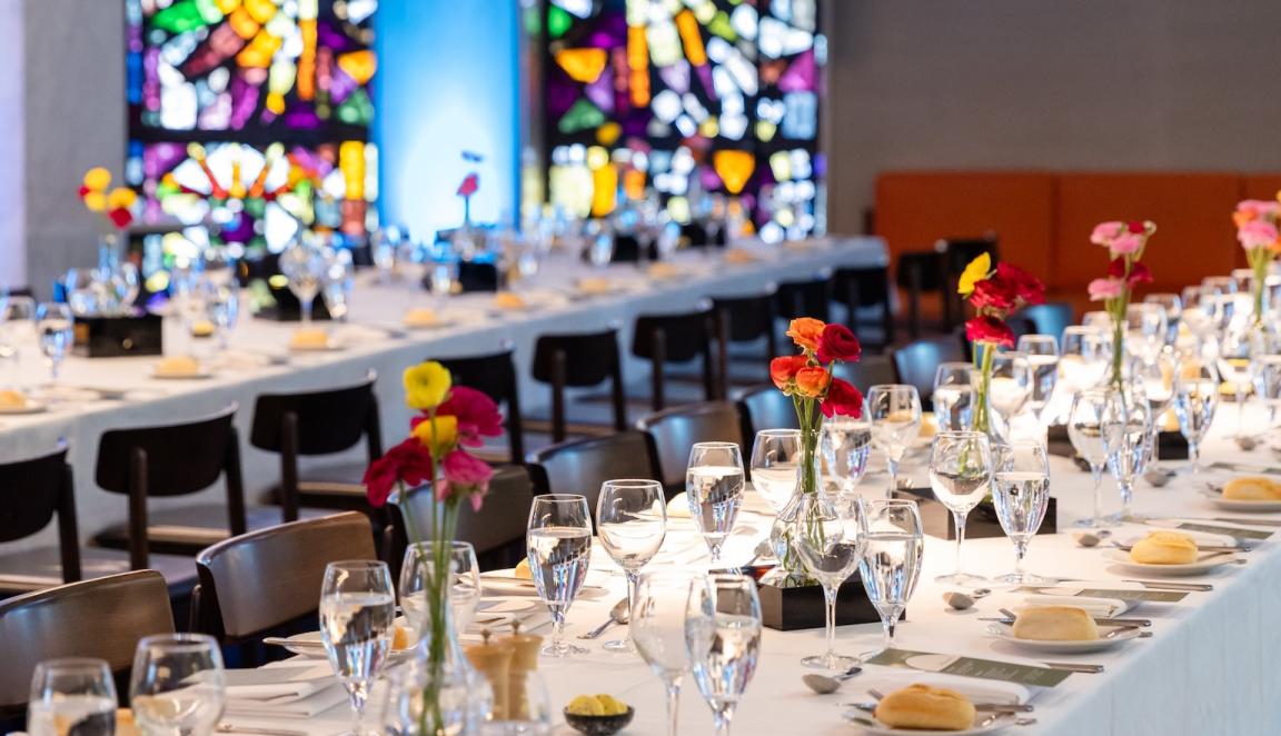 Bookplate cafe set up with long tables with white tablecloths, flowers, glasses and bread rolls