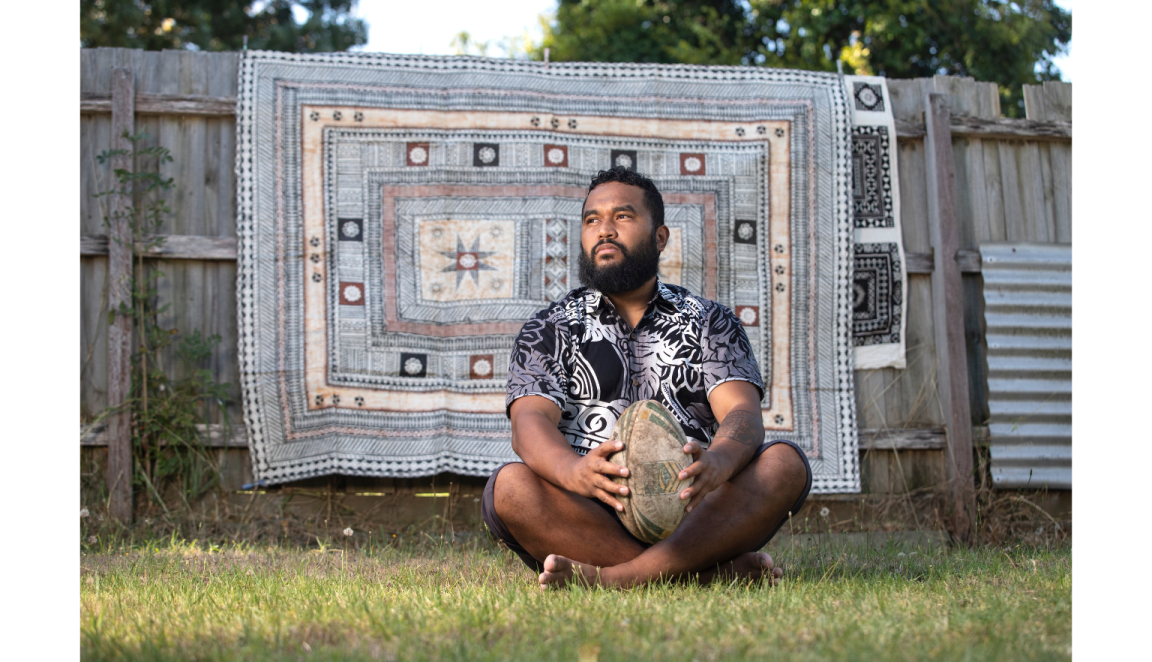 Fijian athlete Dylan Wolfgramm sitting on the ground with a ball