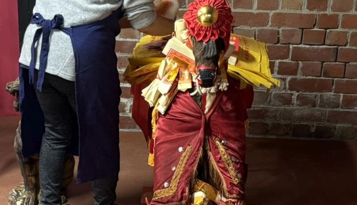 A person stands next to the statue of a horse and applies dressings to it. 