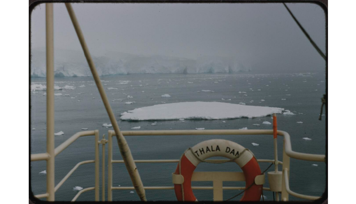 Picture of the shoreline of Antarctica from a ship, some of the ships metal beams crossing the picture