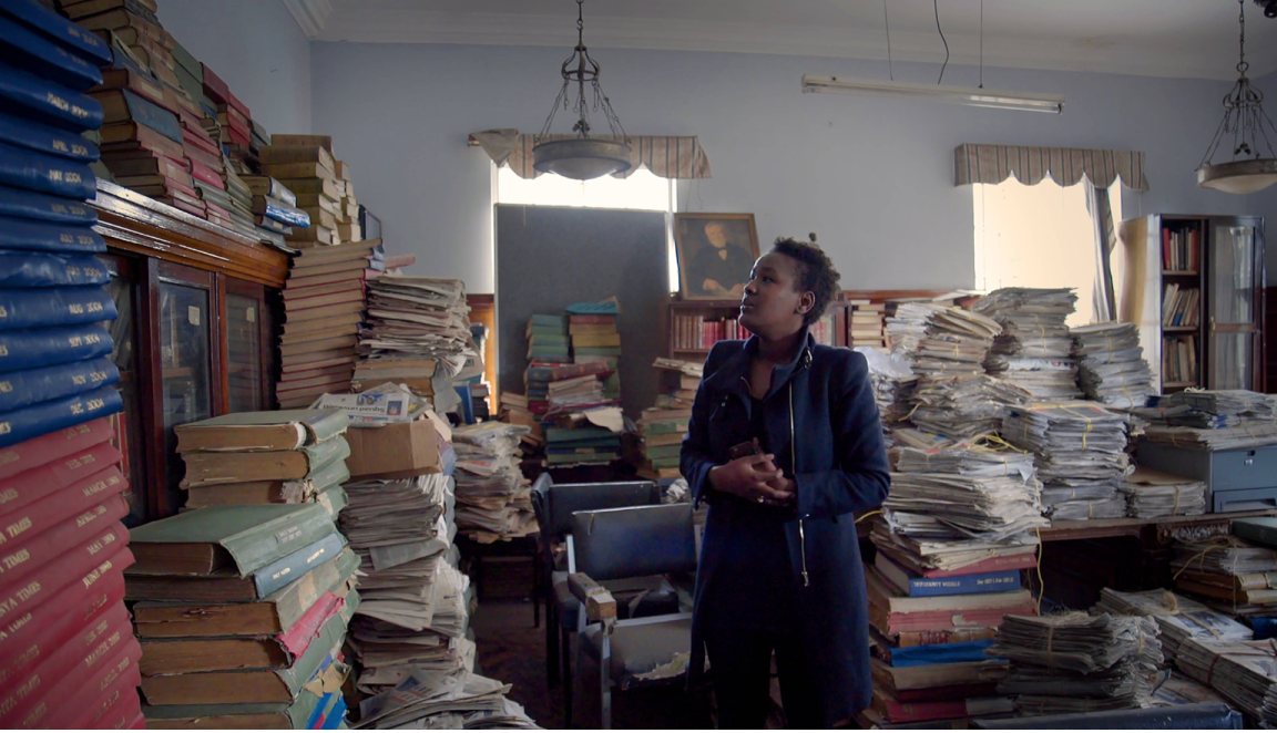 A woman standing in a room walls lined with books