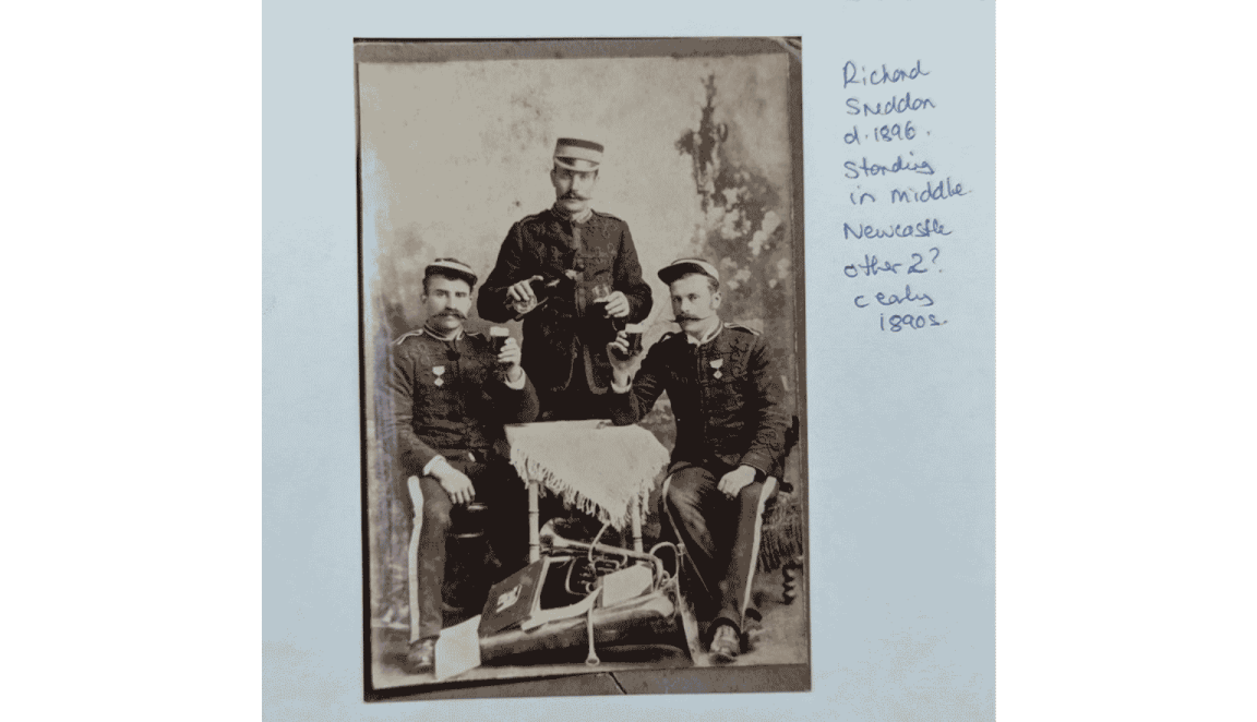A sepia photograph featuring three men in formal attire, posing together.