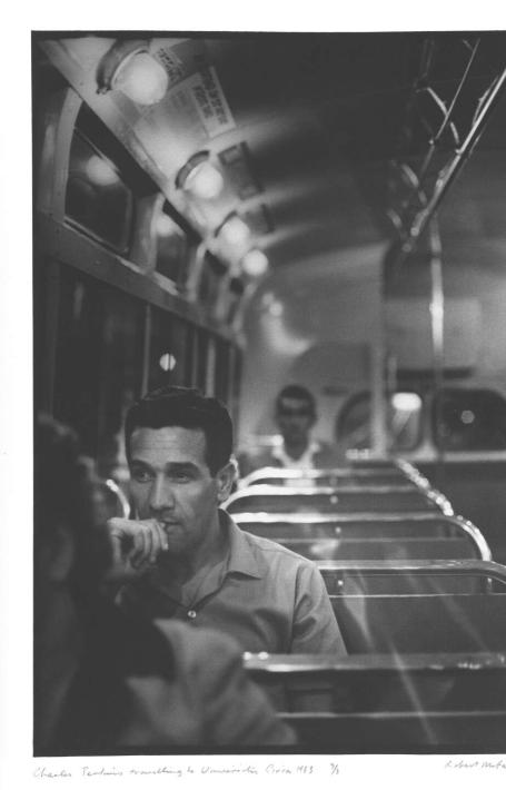 A black and white photo of a man sitting on a train