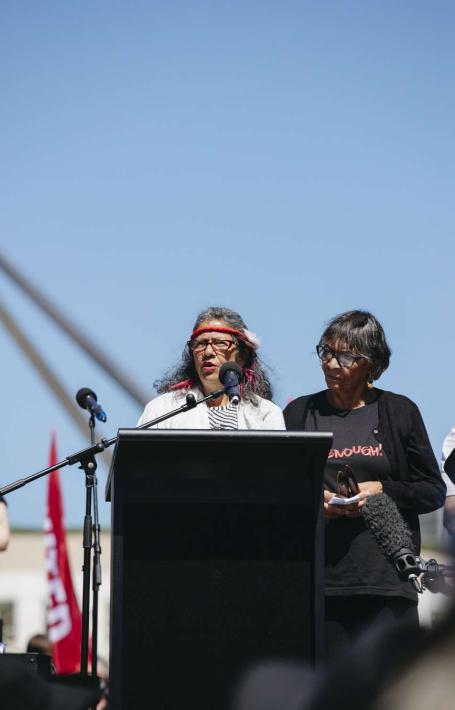 First Nations Elder Aunty Violet Sheridan standing at a lecturn on the lawns of Parliament House