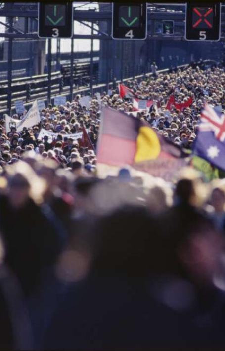 Sydney Harbour Bridge crowded with people, with Aboriginal and Australian flags being held up