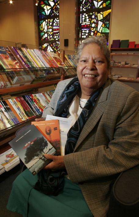 Author Doris Pilkington smiling holding up copies of her books in the National Library Bookshop