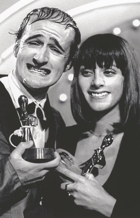 Black and white photo of Norman Gunston and Denise Drysdale smiling and holding up two Logie Awards trophies