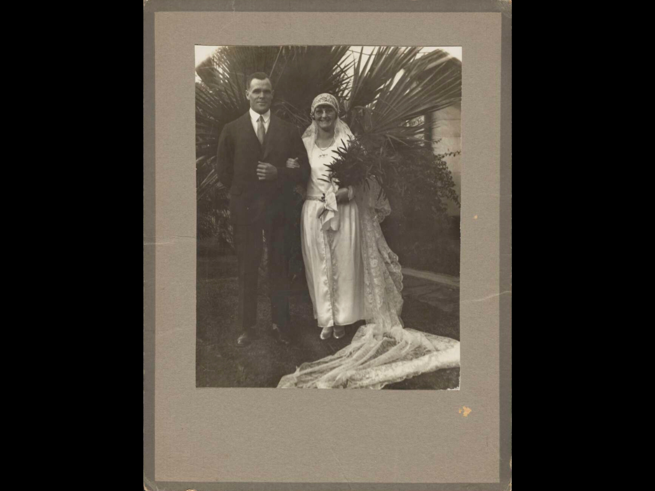 A man and woman pose for their wedding portrait in this image. The man is on the left hand side and the woman, the first to wear the Lockhart family’s wedding veil, is on the right. 