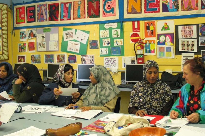 Women sit at a table talking to each other