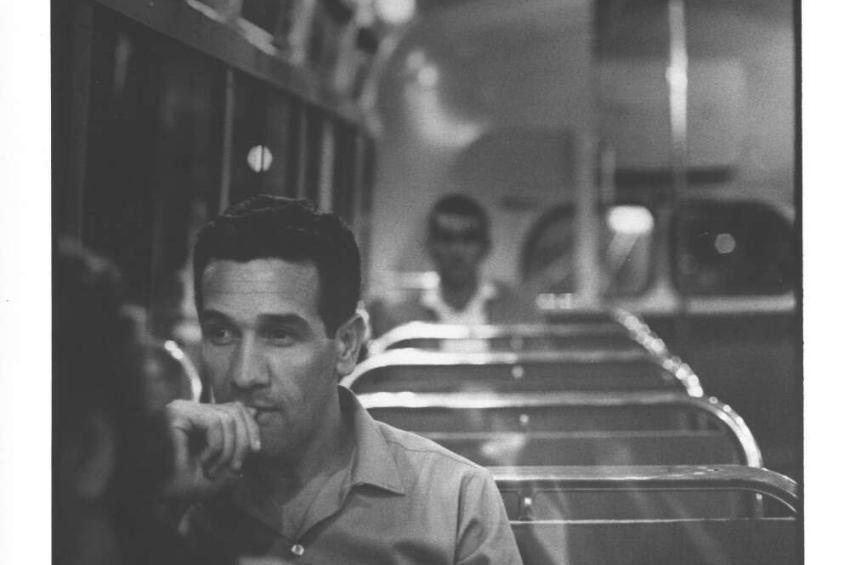A black and white photo of a man sitting on a train