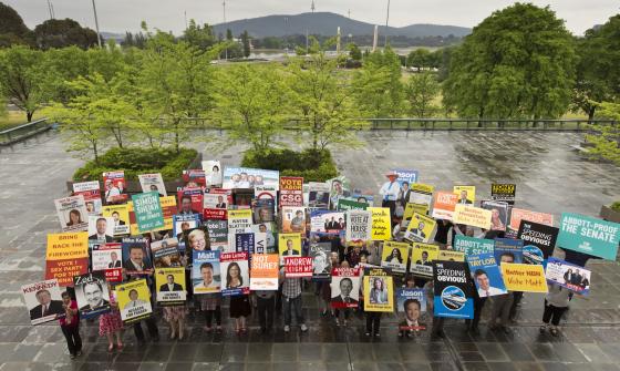 People standing holding colourful corflutes/posters from the 2013 election