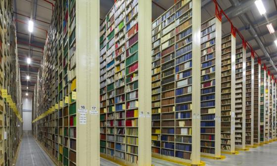 Rows of very tall, large bookshelves (stacks) in a warehouse