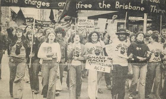 A sepia image of a group of people marching in a protest for Australian First Nations land rights