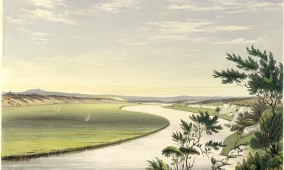 A calm river snakes into the distance, with green grass on one side and trees on the other