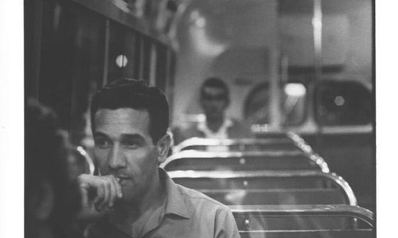 A black and white photo of a man sitting on a train