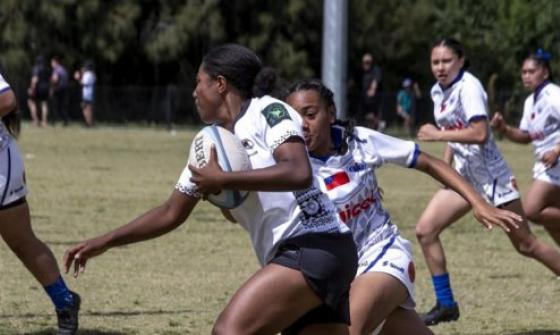 Five girls playing a rugby game on a rugby pitch