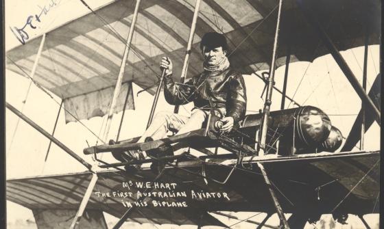 Man in a leather jacket and cap seated in an old biplane
