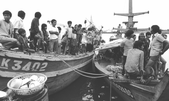 Two boats with rope hanging between them filled with men, women and children coming from Vietnam