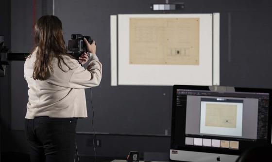 A woman taking a photo of an old manuscript